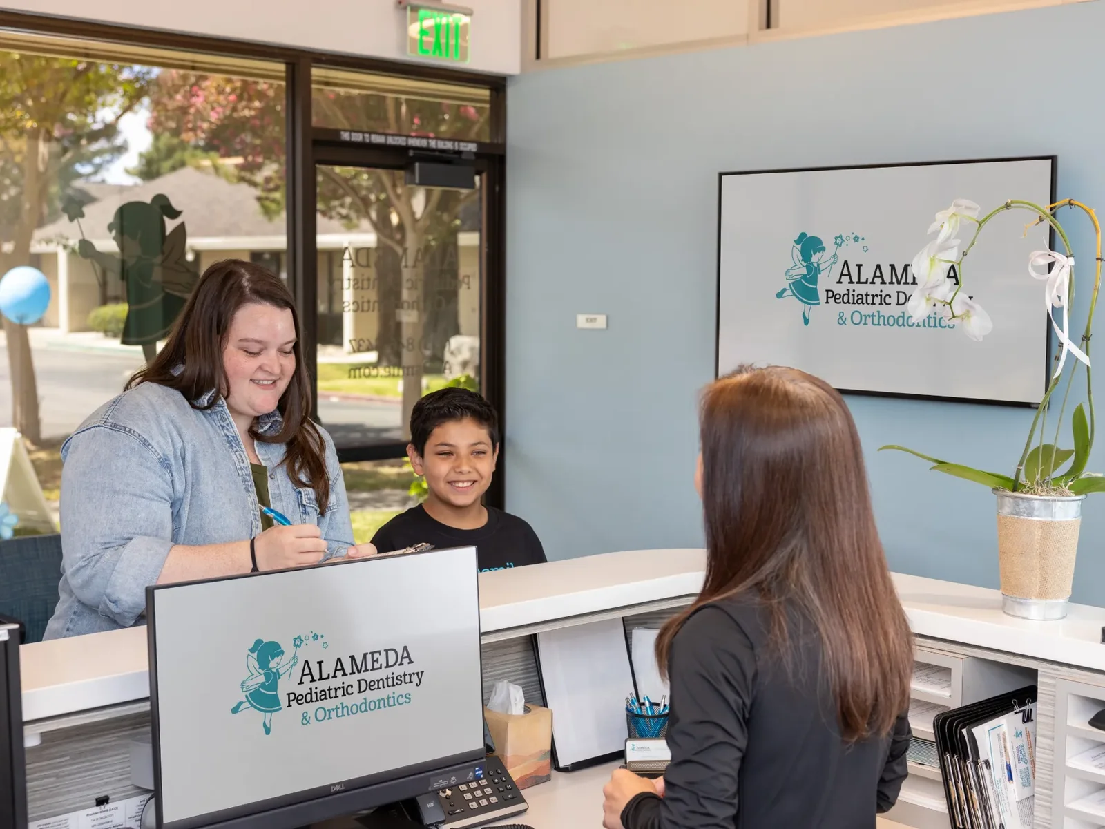 A staff member checking in a family at the Pleasanton front desk