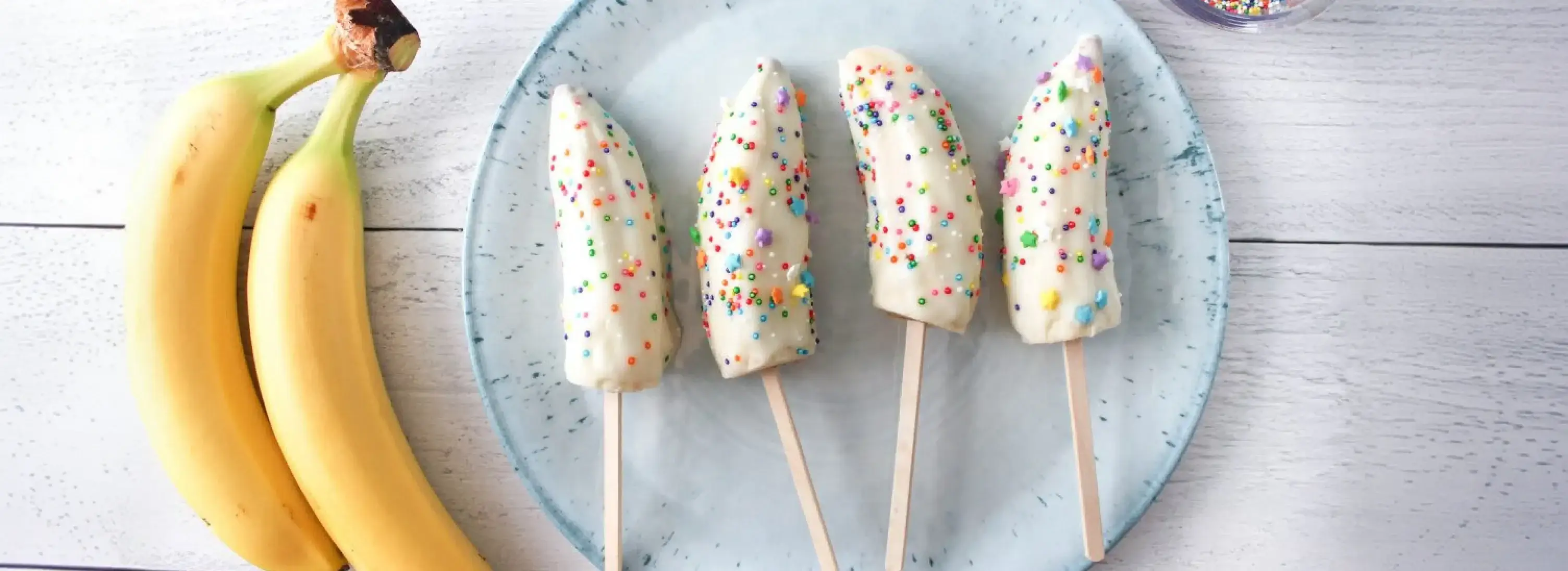 A yogurt-dipped frozen banana pop covered in sprinkles