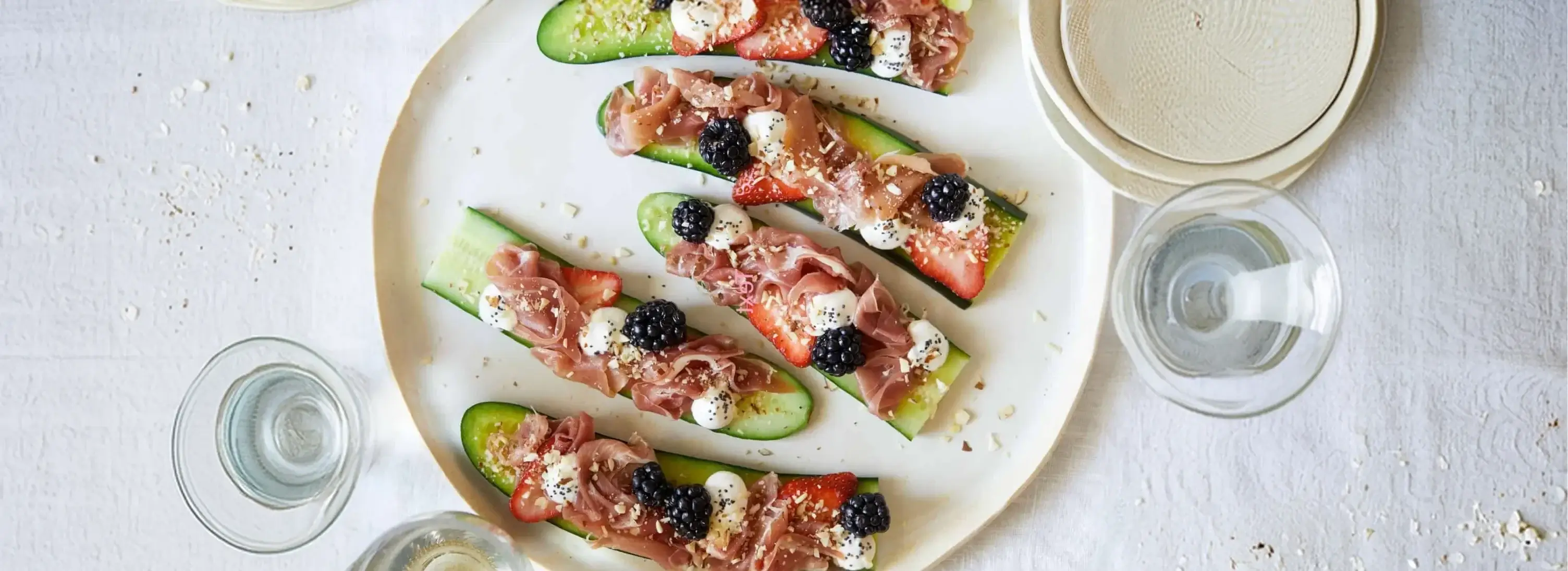 Cucumber crostini topped with prosciutto, strawberries, blackberries, and creme fraiche