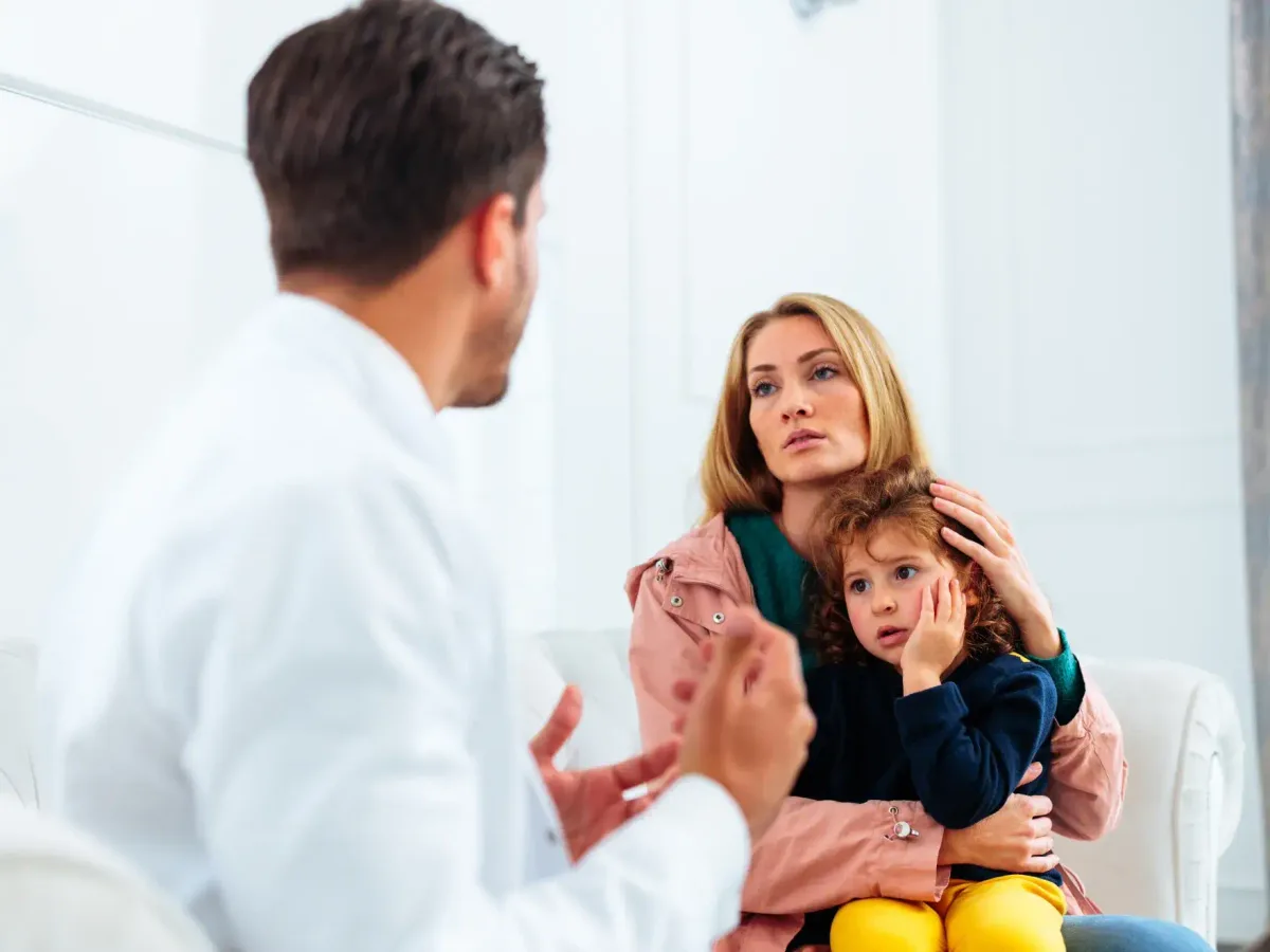 A dentist speaking with a concerned mother and child during an emergency visit