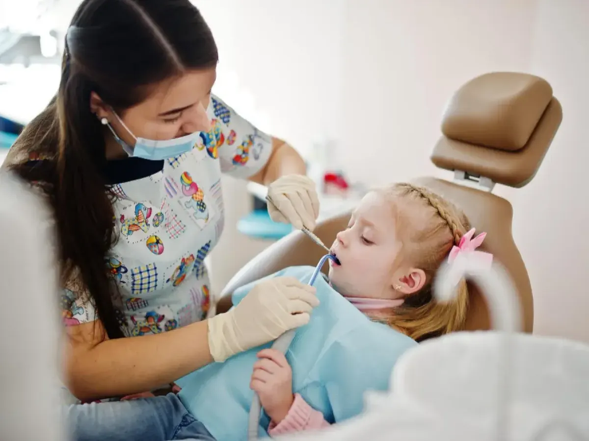 A pediatric dentist examining a young patient's teeth