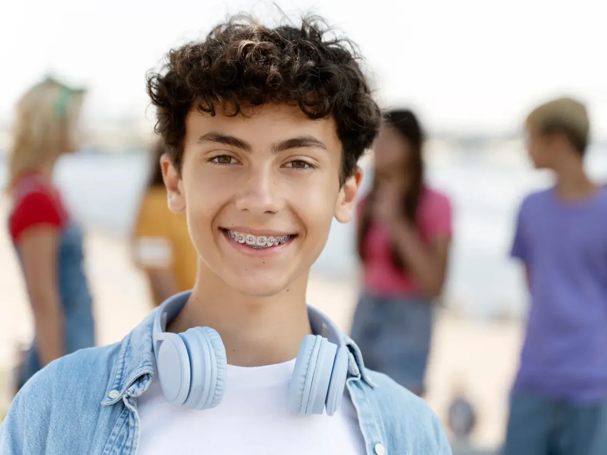 A teenage patient with braces smiling outdoors