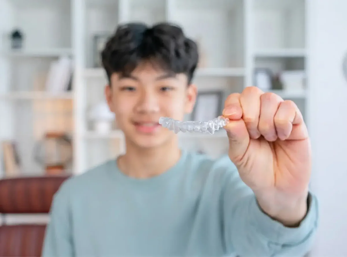 A teenage patient holding a clear aligner
