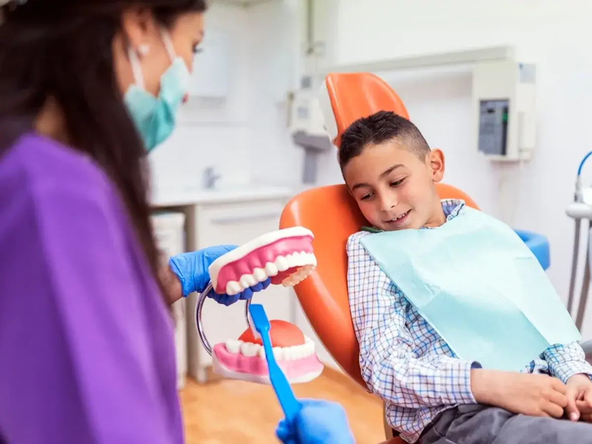A dentist showing a young patient a teeth model during a visit